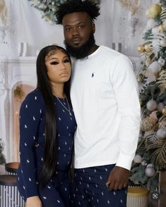 a man and woman posing in front of a christmas tree