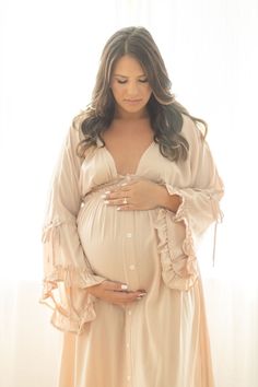 a pregnant woman wearing a long dress and holding her belly