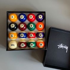 an open box with pool balls and numbers on the inside, sitting next to it