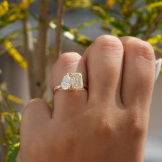 a person's hand with a ring on it and yellow flowers in the background