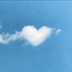 an airplane flying in the sky with a cloud shaped like a heart on it's side