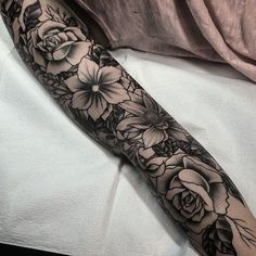 a woman's arm with flowers and leaves tattooed on the forearm, in black and white