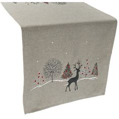 a table runner with a deer in the snow on it and christmas trees behind it