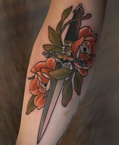 a tattoo on the leg of a person with a knife and flowers around it,