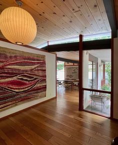 a room with wood flooring and large painting on the wall next to glass doors