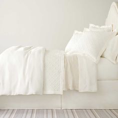 a bed with white sheets and pillows on it