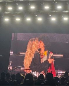 two women are kissing on stage in front of an audience