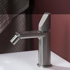 a bathroom faucet that is on top of a white counter next to a red wall