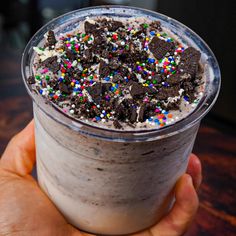 a hand holding a cup filled with ice cream and sprinkles