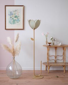 two vases with flowers and plants in them on the floor next to a table