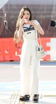 a woman in white overalls standing on the street