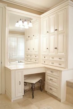 a white kitchen with lots of cabinets and drawers next to a bathtub in the corner