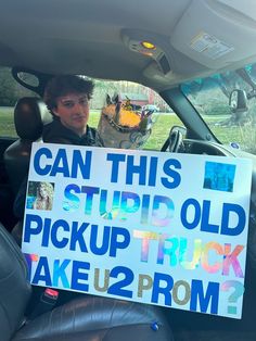 a man sitting in the back seat of a car holding a sign