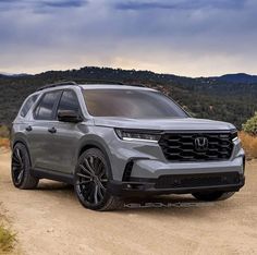 the front end of a silver honda passport parked on a dirt road