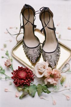 a pair of high heeled shoes sitting on top of a tray next to flowers