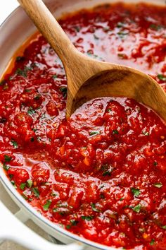 a wooden spoon in a pot filled with marinara sauce