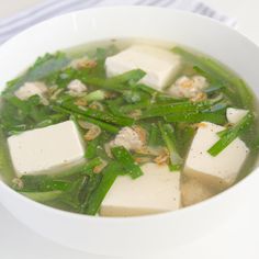 a white bowl filled with green vegetables and tofu