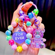 a hand holding a bunch of colorful beads and charms with the words for ever written on it