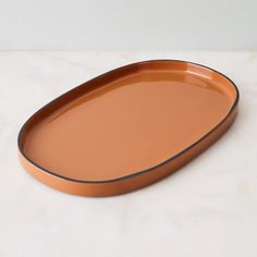 an orange oval serving tray on a marble countertop