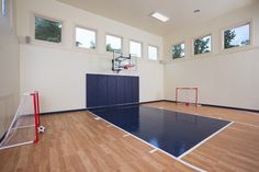 an indoor basketball court in the middle of a room with hard wood floors and windows