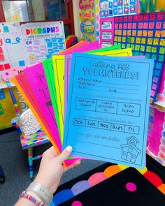 a person holding up a sign in front of colorful bulletin boards with writing on them