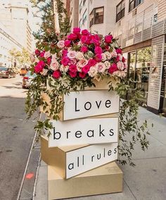 a sign that says love breaks all rules with flowers in it on the side walk