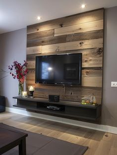 a flat screen tv mounted to the side of a wooden wall in a living room