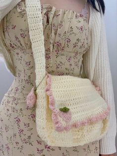 a woman holding a crocheted purse with flowers on the front and bottom part