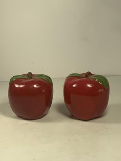 two red peppers sitting side by side on a white counter top next to each other