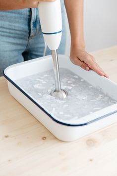 a woman is using a hand mixer to make ice cubes