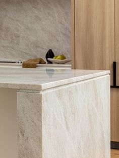 a marble counter top in the middle of a kitchen with wooden cabinets and cupboards