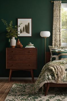 a bedroom with dark green walls and wooden furniture, including a bed covered in a floral comforter