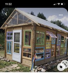 a small house made out of windows and wooden sidings on the side of a field