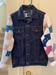 a denim jacket hanging up on a door with patchwork sleeves and buttons in the back