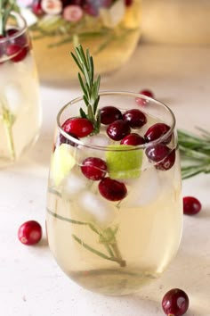 two glasses filled with liquid and cranberries on top of a wooden cutting board