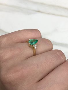 This ring features a 1.06-carat natural Colombian emerald, pear cut from the famous Muzo mines. Set in a secure two-prong setting, this extraordinary emerald has a stunning green color and very good eye clarity, Minor imperfections are normal for genuine Colombian emeralds. Three brilliant round diamonds accent the emerald on either side. Excellent colorless diamonds with VS clarity highlight the pear cut emerald. Set in silky 18K yellow gold. Perfect for everyday wear. Metal Purity: 18K Yellow Teardrop Emerald Ring With Prong Setting, Green Teardrop Emerald Ring With Brilliant Cut, Emerald Teardrop Ring With Brilliant Cut, Fine Jewelry Emerald Ring With Pear Gemstone, Emerald Pear-shaped Ring With Prong Setting, Yellow Gold Pear-shaped Emerald Ring, Emerald Pear Shaped Ring With Prong Setting, Pear-shaped Emerald Ring In Fine Jewelry Style, Pear-shaped Emerald Ring, Fine Jewelry