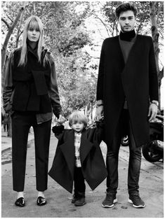 a man, woman and child are walking down the street in black clothes with their hands on each other's hips