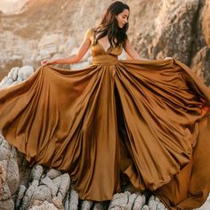 a woman in a brown dress standing on rocks