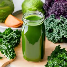 a jar filled with green liquid surrounded by vegetables