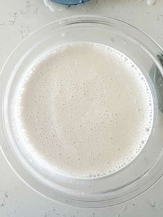 a glass bowl filled with white liquid next to a spoon