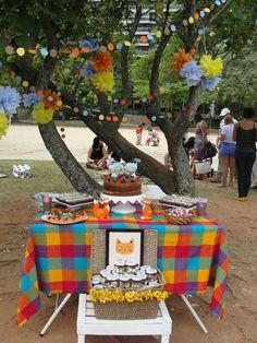 a picnic table set up under a tree with paper pom poms hanging from the branches