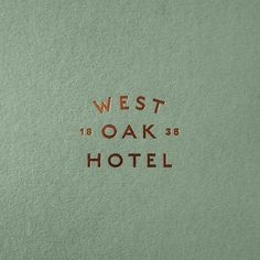 the words west and oak hotel written in gold on a light green background with brown lettering