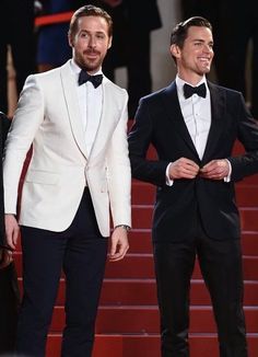 two men in tuxedos standing next to each other on the red carpet at an event