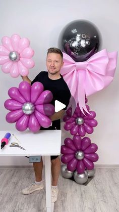 a man holding balloons and flowers in his hands