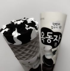 two ice cream cones with black and white toppings on them, sitting next to each other