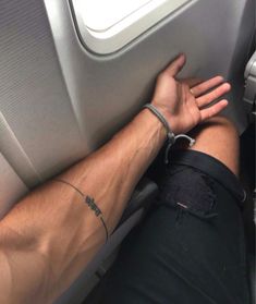 a man with his arm wrapped around the seat of an airplane, holding onto another person's wrist