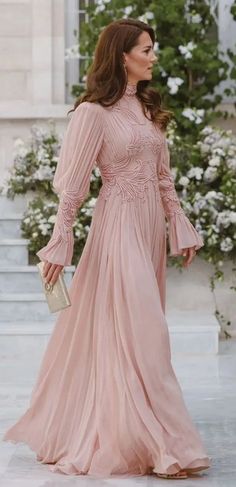 a woman in a pink dress is walking down the street with her hand on her hip