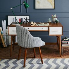 a desk with a chair, lamp and pictures on the wall