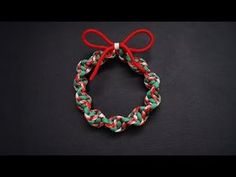 a red, white and green bracelet with a bow on the end is sitting on a black surface