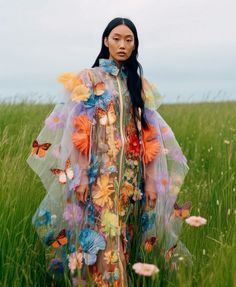 a woman standing in a field with butterflies on her dress